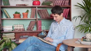 一个年轻人坐在家里的图书馆里看书，一个穿着蓝色衬衫和牛仔裤的人拿着一本书看书。